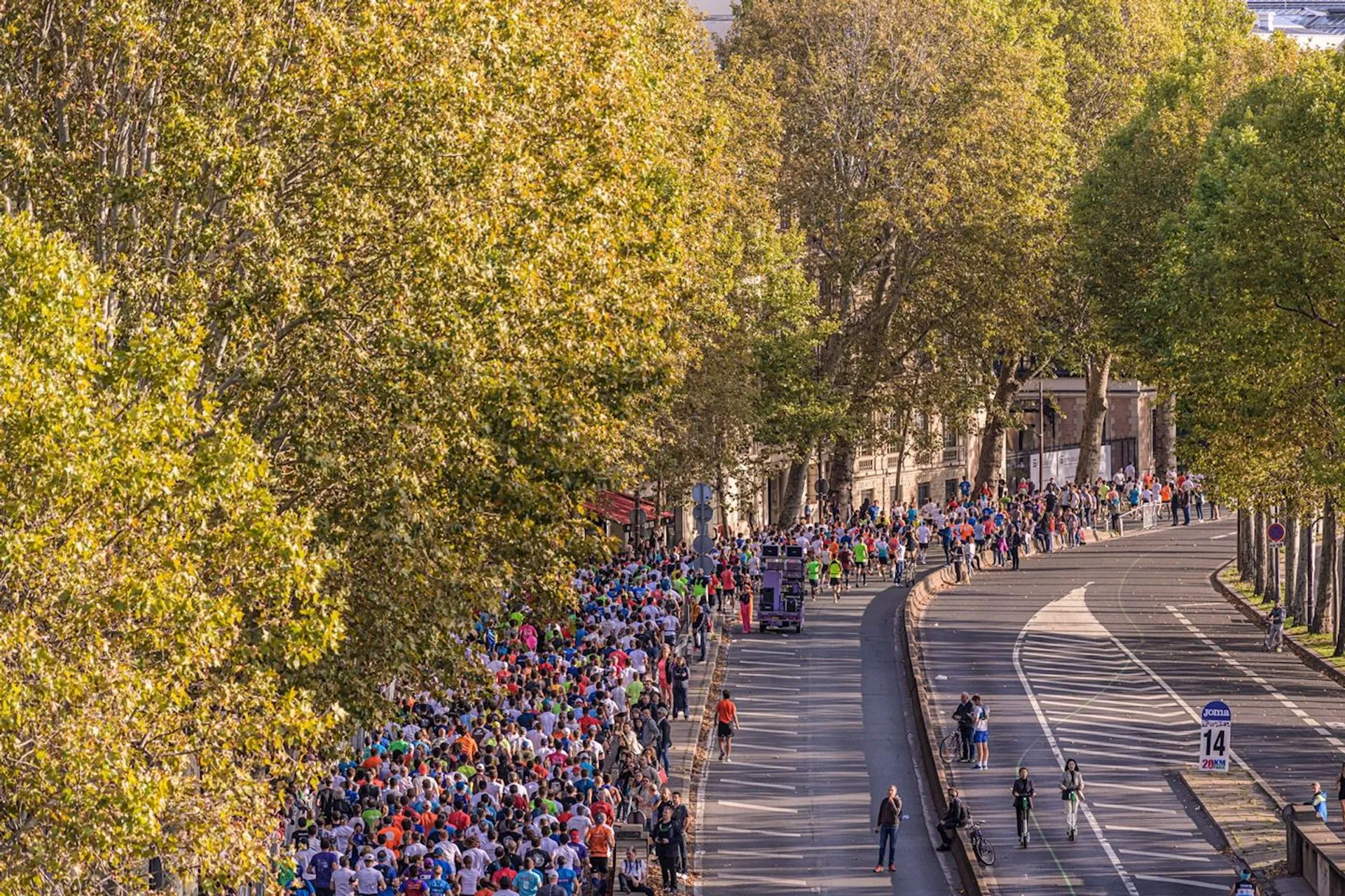The image shows a large group of people participating in a road running event, likely