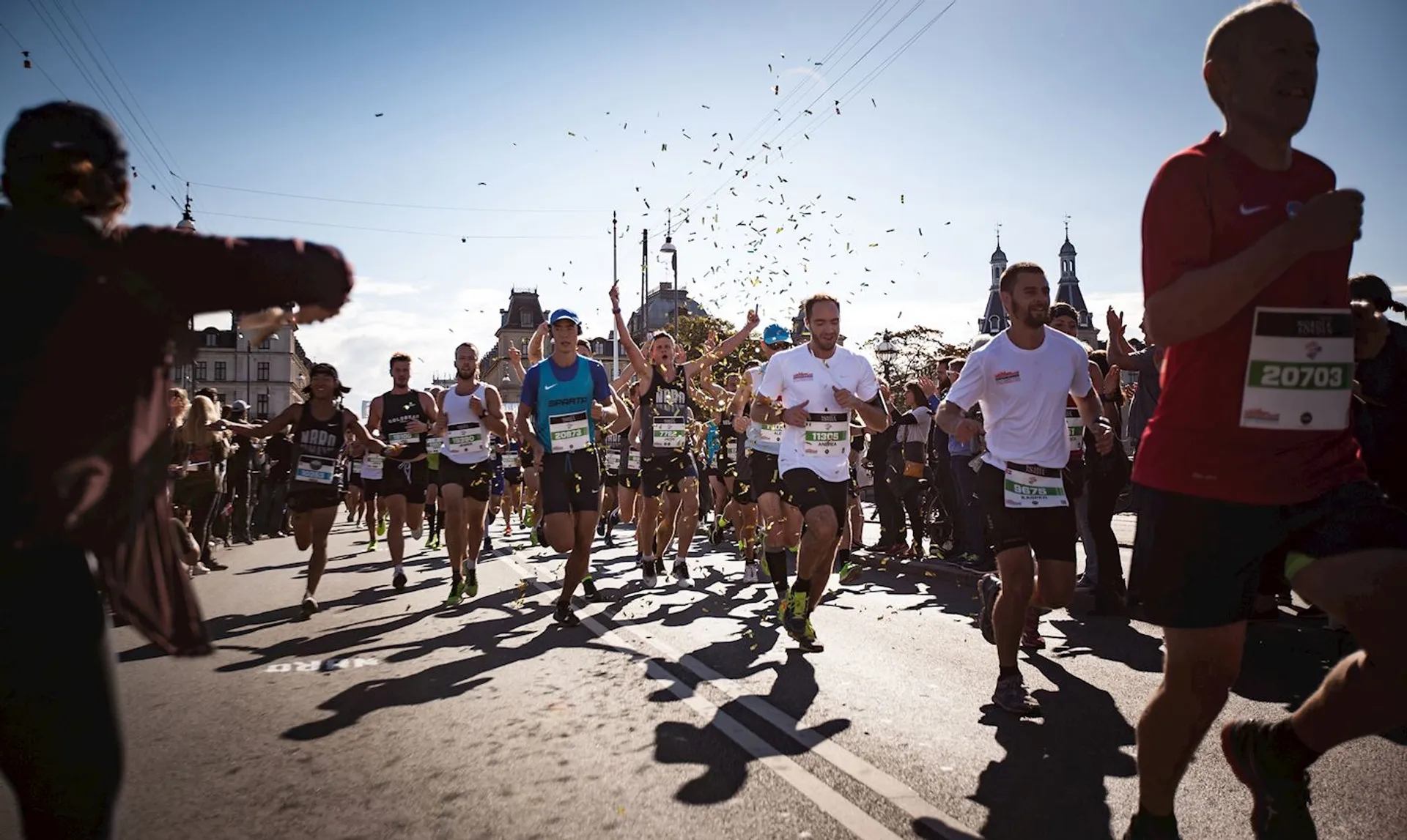 The image shows a group of runners participating in a road race, likely a marathon