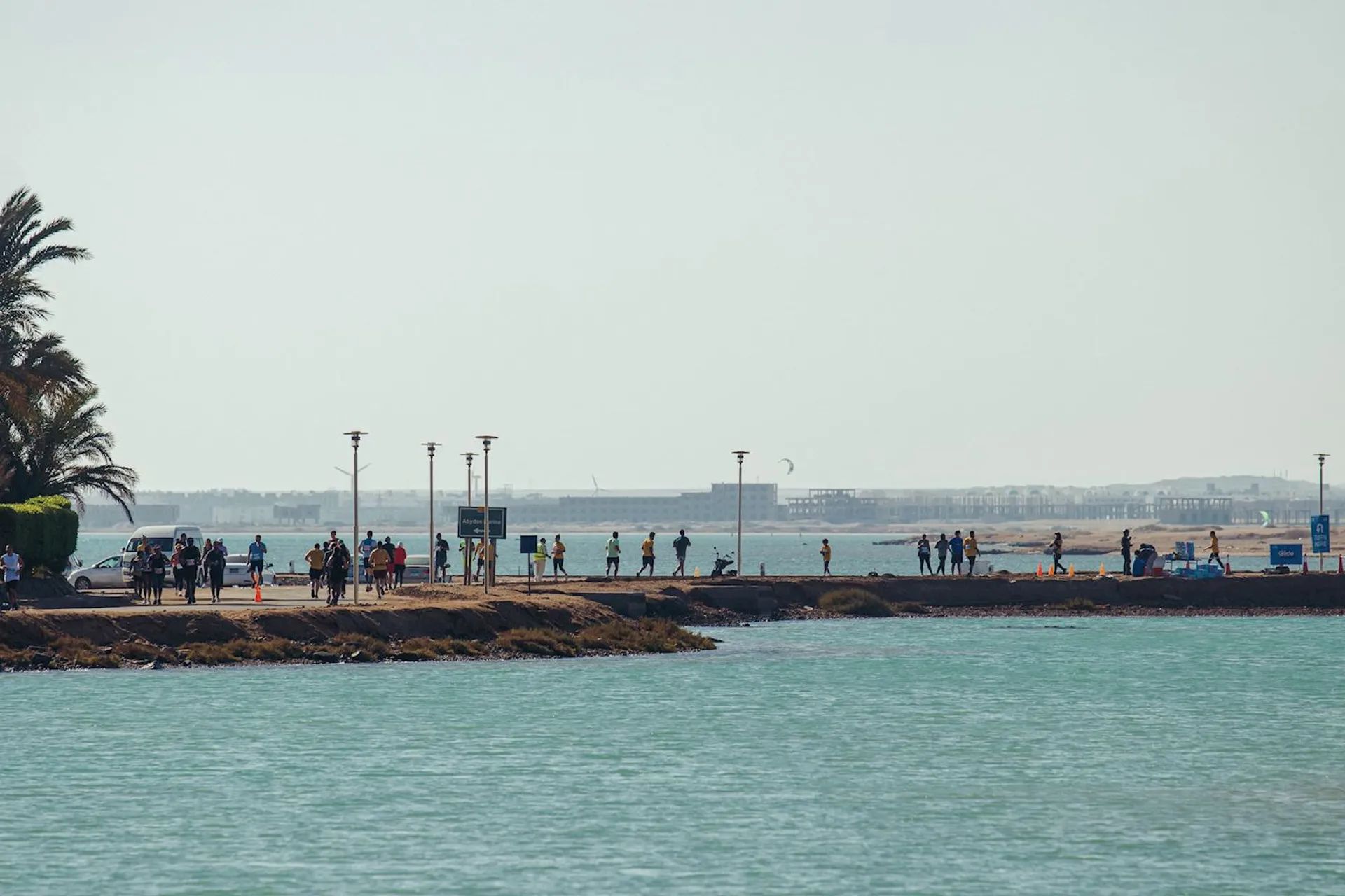 The image shows a coastal scene where a group of people are walking along a prom