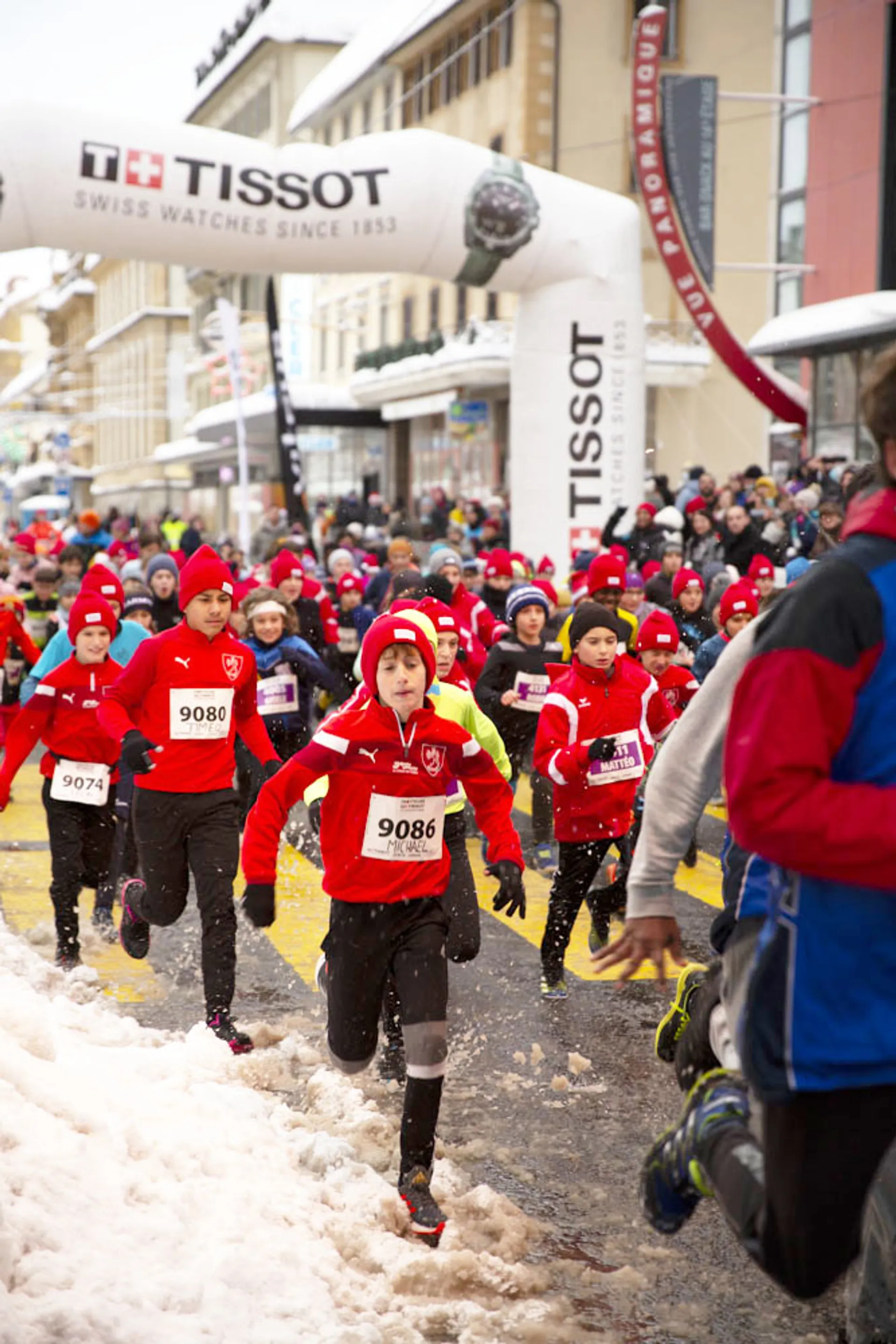 The image shows a group of young participants running in a snow-covered street during a