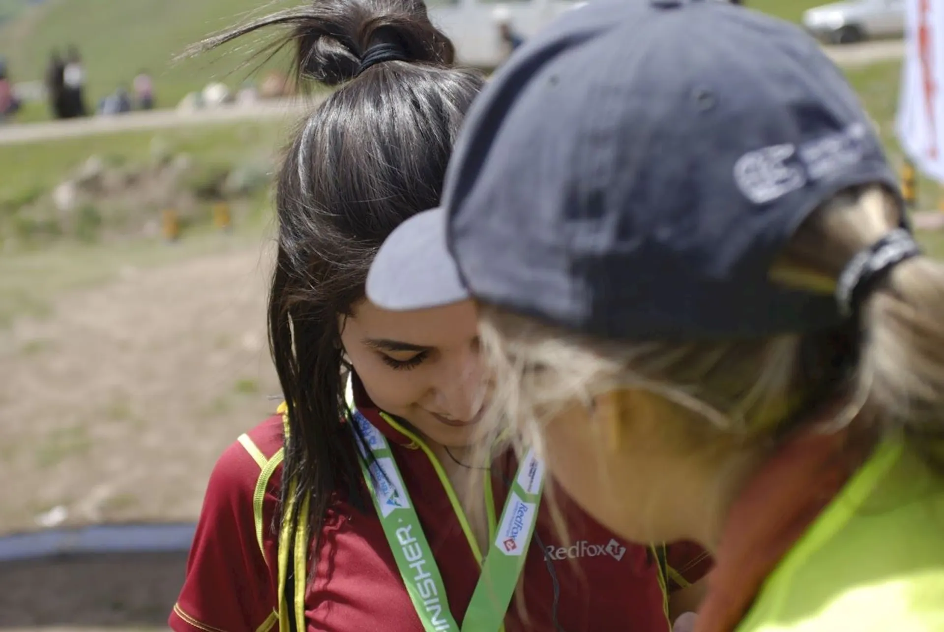 The image shows two people engaged in an interaction, possibly at an outdoor event or