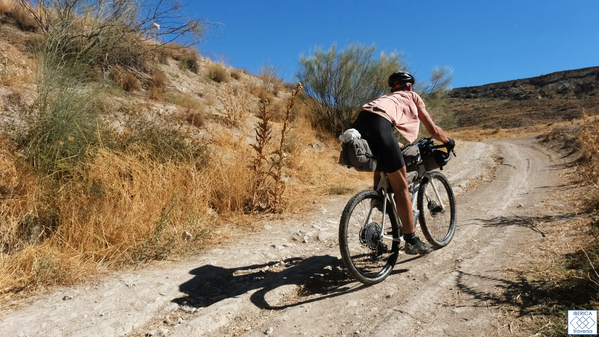 This image shows a person riding a bicycle on a dirt trail. The cyclist is