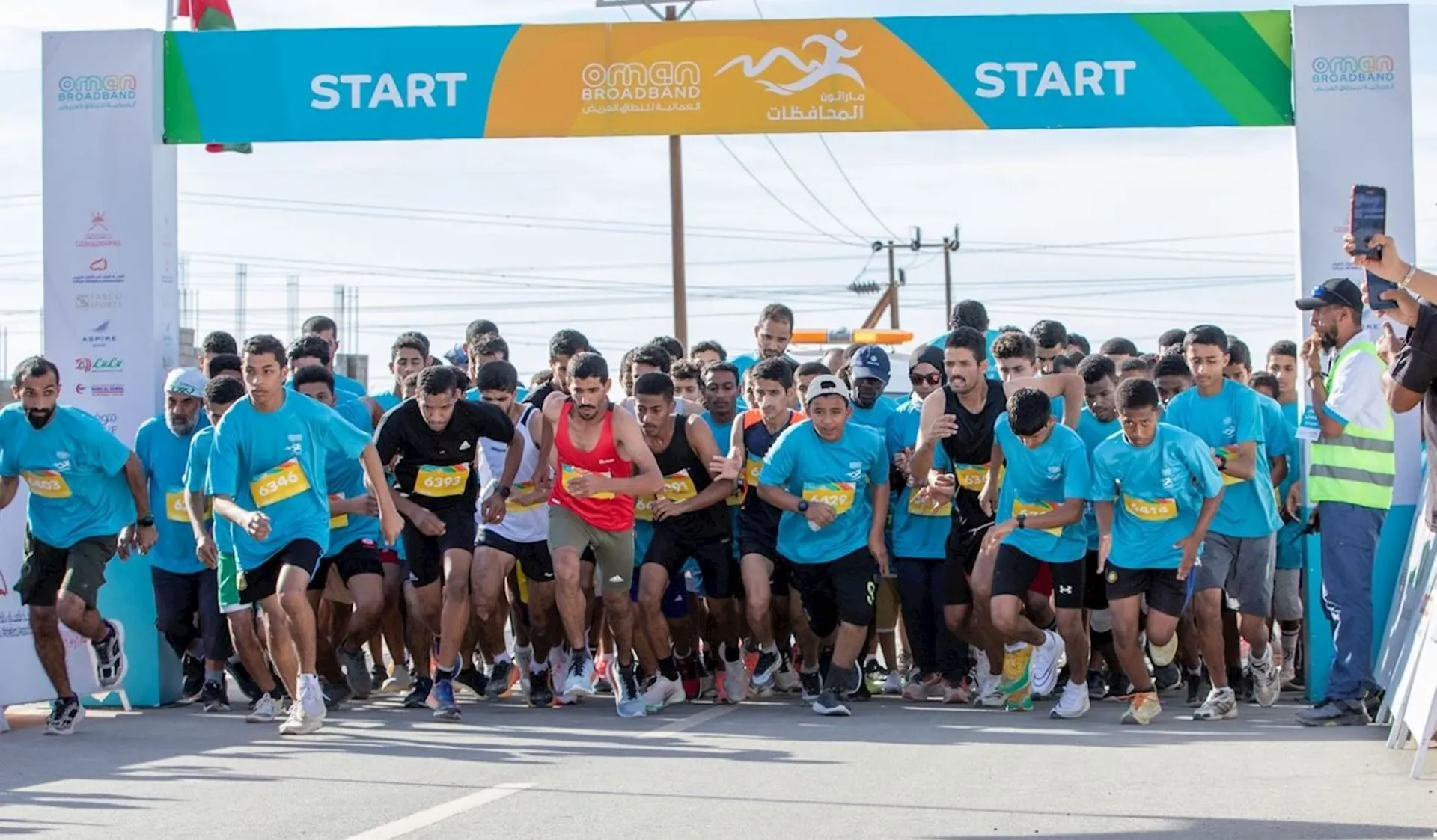 The image shows a group of people at the start line of a running event or