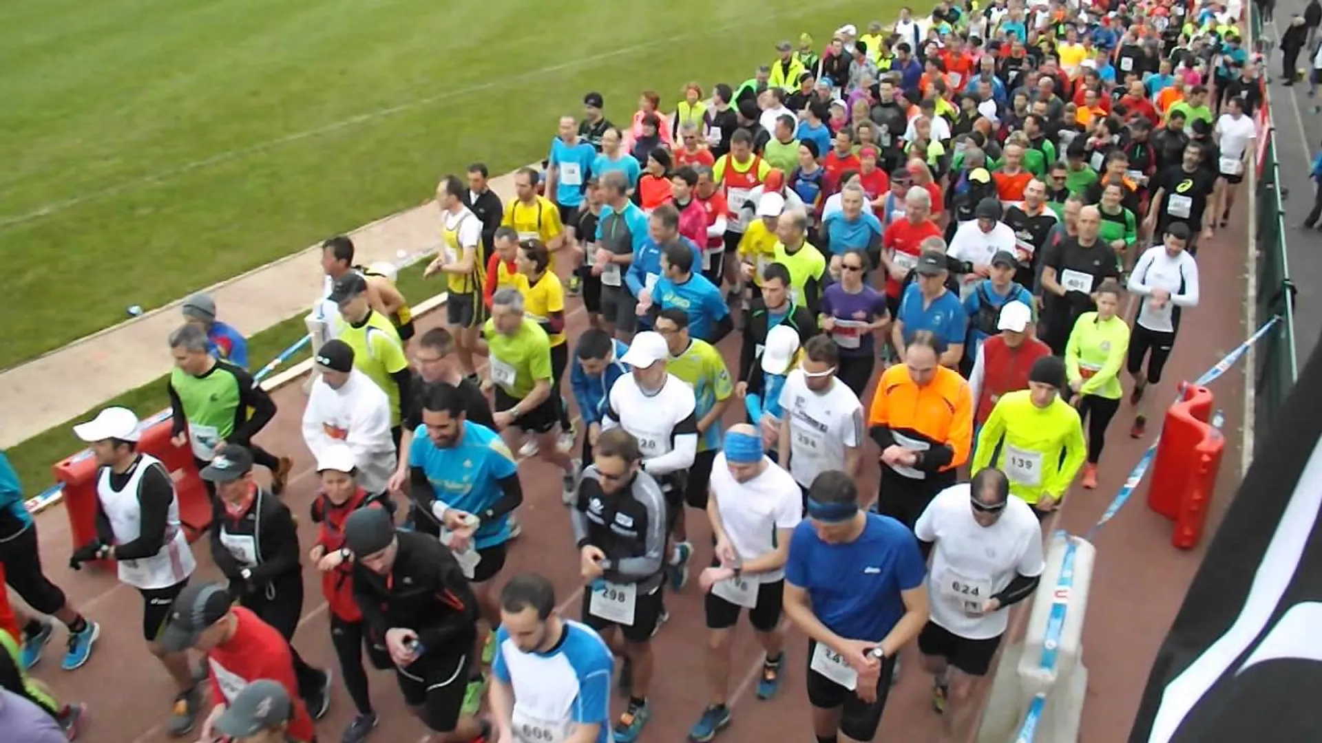 The image depicts a large group of runners at the start of a race, possibly
